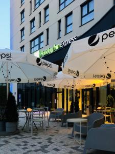 a patio with tables and umbrellas in front of a building at Holiday Inn Express Warsaw - Mokotow, an IHG Hotel in Warsaw