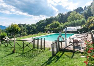 a pool with chairs and umbrellas in a yard at Villa La Ginestra con piscina privata in Umbertide