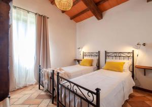 two beds with yellow pillows in a room with a window at Villa La Ginestra con piscina privata in Umbertide