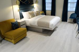 a bedroom with a large bed and a yellow chair at NOX Waterloo in London