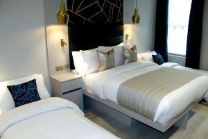 two beds in a hotel room with white sheets at NOX Waterloo in London