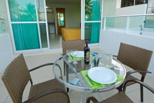 a glass table with a bottle of wine and chairs at Nord Easy Green Sunset in João Pessoa