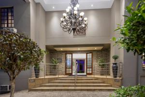 un gran vestíbulo con escaleras y una lámpara de araña en The Cycad Lodge & Chalets, en Nelspruit
