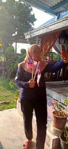 a woman holding an american flag and tooth brushes at Homestay Damai Sri Kota in Kepala Batas