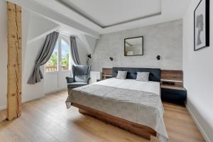 a bedroom with a bed and a chair at Victus Apartamenty, Apartamenty Panamera in Sopot