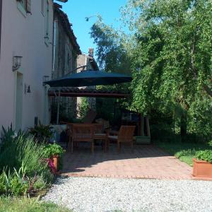 a patio with a table and an umbrella at Una Casa di Campagna in Dossobuono