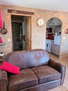 a brown leather couch in a living room with a clock at L Appicciu in Ventiseri