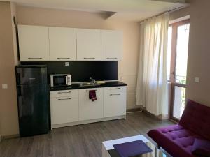 a kitchen with white cabinets and a black refrigerator at Апартамент ЕЛИ in Pleven