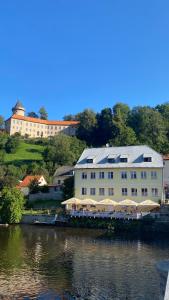 un grand bâtiment blanc à côté d'une étendue d'eau dans l'établissement Rožmberk Inn, à Rožmberk nad Vltavou