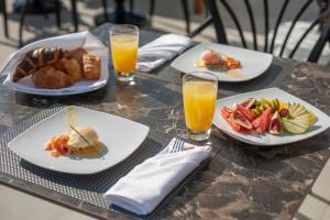 a table with plates of food and glasses of orange juice at Vivid Blue Serenity Resort in Sveti Stefan