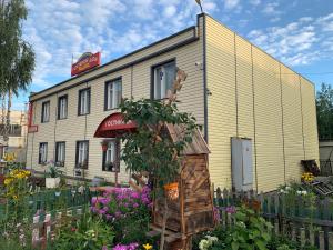 un edificio con un jardín de flores delante de él en Raduga Guest House, en Petrozavodsk