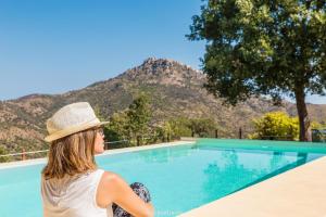 a woman wearing a hat sitting next to a swimming pool at Casale Margherita Turismo Rurale in Pollina