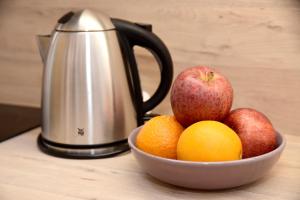 a bowl of fruit with apples oranges and a kettle at Luxury Maisonette in Vittoriosa