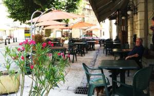 a man sitting at a restaurant with tables and chairs at Auberge du Puits in Souillac