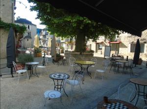 an outdoor patio with tables and chairs and a tree at Auberge du Puits in Souillac