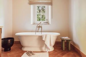a bath tub in a bathroom with a window at Hotel Lou Pinet in Saint-Tropez
