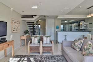 een woonkamer met een bank en stoelen en een keuken bij Whale Coast All-Suite-Hotel - DCC Hotel Group in Hermanus