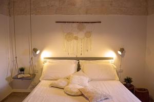 - une chambre avec un lit doté de draps et d'oreillers blancs dans l'établissement A volte in collina, à Martina Franca