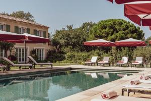 a swimming pool with lounge chairs and umbrellas at Hotel Lou Pinet in Saint-Tropez