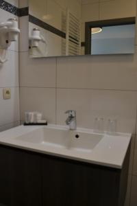 een witte wastafel in een badkamer met een spiegel bij Auberge Le Temps des Saveurs in Paliseul