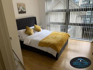 a bedroom with a bed with a yellow blanket on it at Angel Lee Serviced Accommodation, Diego London, 1 Bedroom Apartment in London