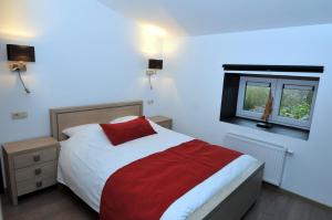 um quarto com uma cama vermelha e branca e uma janela em Auberge Le Temps des Saveurs em Paliseul
