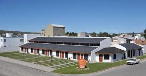 - un grand bâtiment blanc avec un panneau devant dans l'établissement Arenas Blancas, à Puerto Madryn