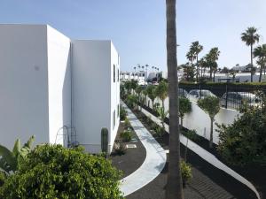 Un edificio blanco con árboles al lado de una calle. en Playa Park, en Los Pocillos