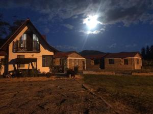 a house with the moon in the sky behind it at CABAÑAS SANTA TERESA in Tibasosa