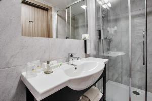 een witte badkamer met een wastafel en een douche bij Golden Tulip Krakow Kazimierz in Krakau