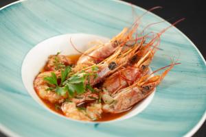 a bowl of food with shrimp on a blue plate at Vivid Blue Serenity Resort in Sveti Stefan