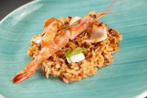 a blue plate of food with shrimp on rice at Vivid Blue Serenity Resort in Sveti Stefan