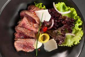 a plate of food with meat and a salad at Vivid Blue Serenity Resort in Sveti Stefan