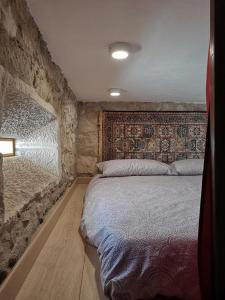 1 dormitorio con 1 cama con pared de piedra en Yasmine 212 en Ançã