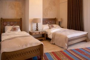 a bedroom with two beds and a table with two lamps at Boutique ETHNO HOTEL in Gyumri