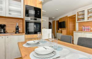 eine Küche und ein Esszimmer mit einem Tisch mit Tellern und Weingläsern in der Unterkunft Apartments Maiskogelblick in Piesendorf