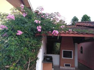 una casa con flores rosas a un lado. en Casa - Flores Encantadas, en Campos do Jordão