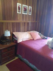 1 dormitorio con 1 cama y 1 mesa con lámpara en Casa - Flores Encantadas, en Campos do Jordão