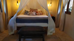 Cama en habitación con dosel y almohadas en Hotel Boutique Chacá en Tulum