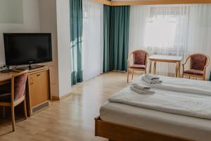 a hotel room with a bed and a flat screen tv at Georgshof in Podersdorf am See