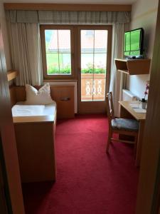 a hotel room with a bed and a desk and window at Landhaus Montana in Gerlos