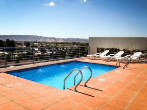 a swimming pool on top of a building with chairs at Apartamentos Terrazas de Talca in Talca