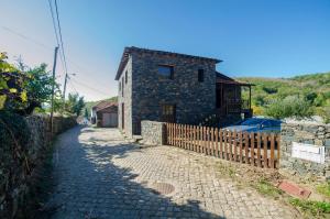 a stone house with a fence next to a street at Casa do Rebelhe in Vinhais