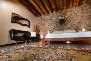 um quarto com uma cama, uma cadeira e uma parede de tijolos em La Bella Verona Wine Suite em Verona