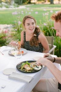 un homme et une femme assis à une table avec une assiette de nourriture dans l'établissement Domaine la Pierre Blanche, à Eygalières