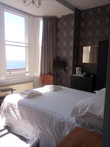 Un dormitorio con una gran cama blanca y una ventana en Glenleigh Bed and Breakfast, en Marazion