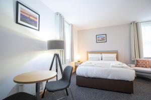 ノリッジにあるWellington Apartmentsのベッド、テーブル、椅子が備わるホテルルームです。