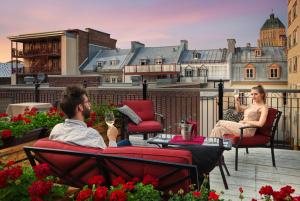 a man and woman sitting on a balcony with a glass of wine at Hotel Manoir D'Auteuil in Quebec City