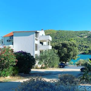 a white building with a parking lot next to a lake at Apartments Vala in Grebaštica