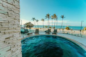 a swimming pool next to a beach with palm trees at Iracema Residence Hotel Flat in Fortaleza